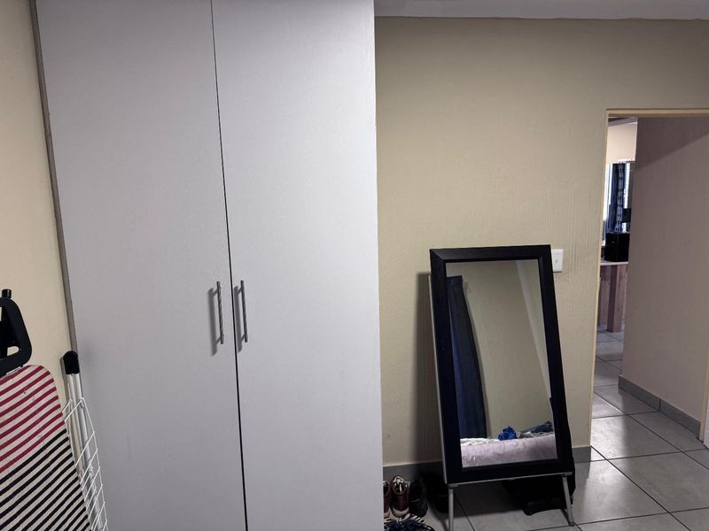 A bedroom interior featuring a white built-in wardrobe and tiled flooring, providing functional storage space within the apartment.