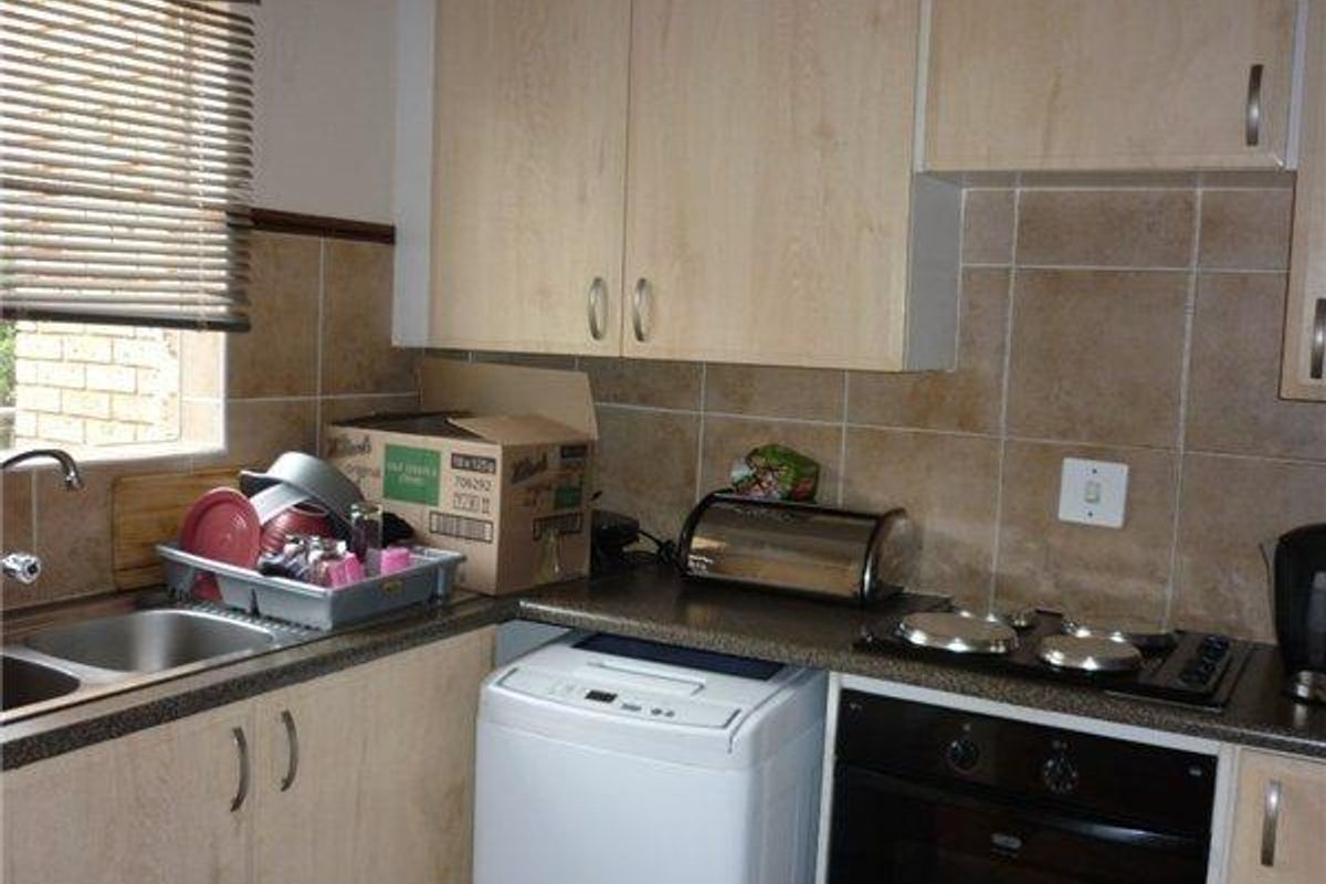 Compact kitchen featuring laminate cabinetry, tiled backsplash, built-in oven, electric hob, and a double bowl stainless steel sink.