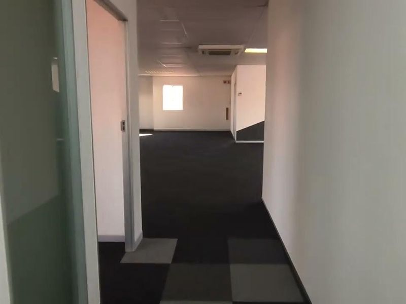 An empty, open-plan office space featuring carpet tiles, a suspended ceiling with recessed lighting, and integrated ducted air conditioning.