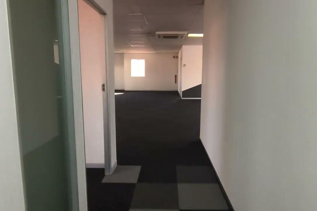 An empty, open-plan office space featuring carpet tiles, a suspended ceiling with recessed lighting, and integrated ducted air conditioning.
