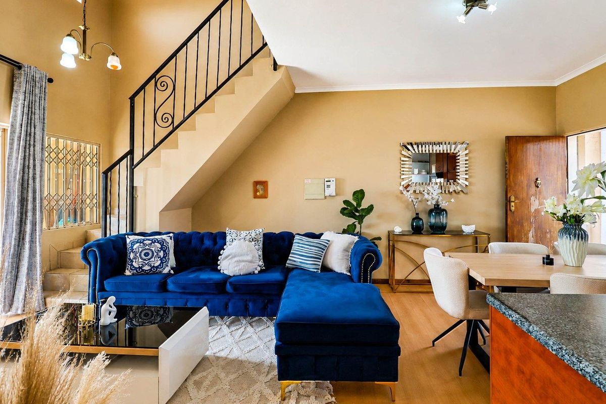 Open-plan living and dining area featuring a prominent staircase with wrought iron railing, laminate flooring, and neutral wall tones.