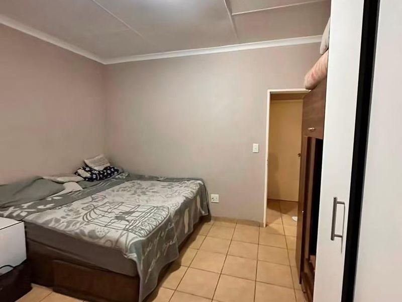 A bedroom featuring tiled flooring, a built-in wardrobe, and a ceiling light fixture. The room requires cosmetic updates to the ceiling and finishes.