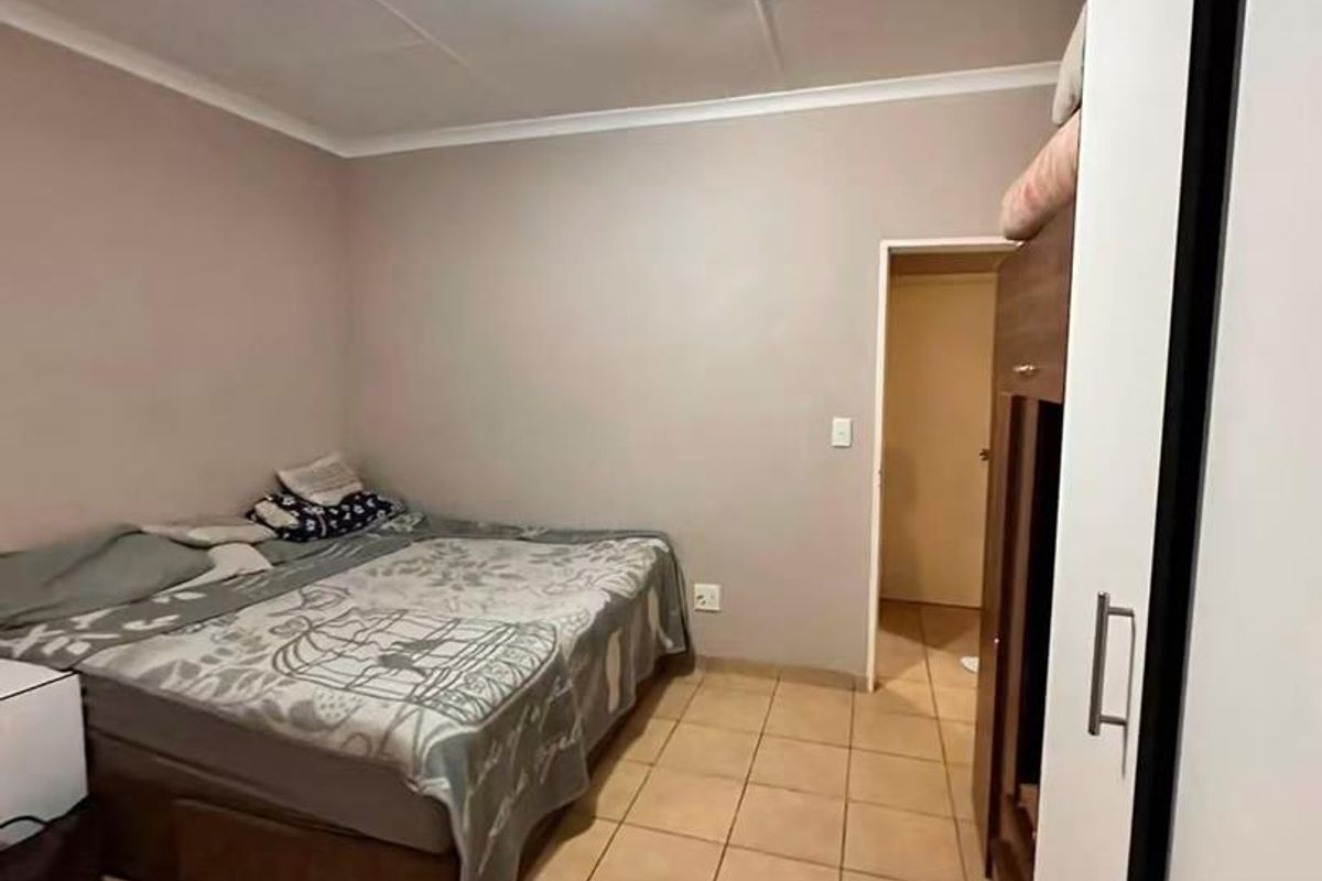 A bedroom featuring tiled flooring, a built-in wardrobe, and a ceiling light fixture. The room requires cosmetic updates to the ceiling and finishes.