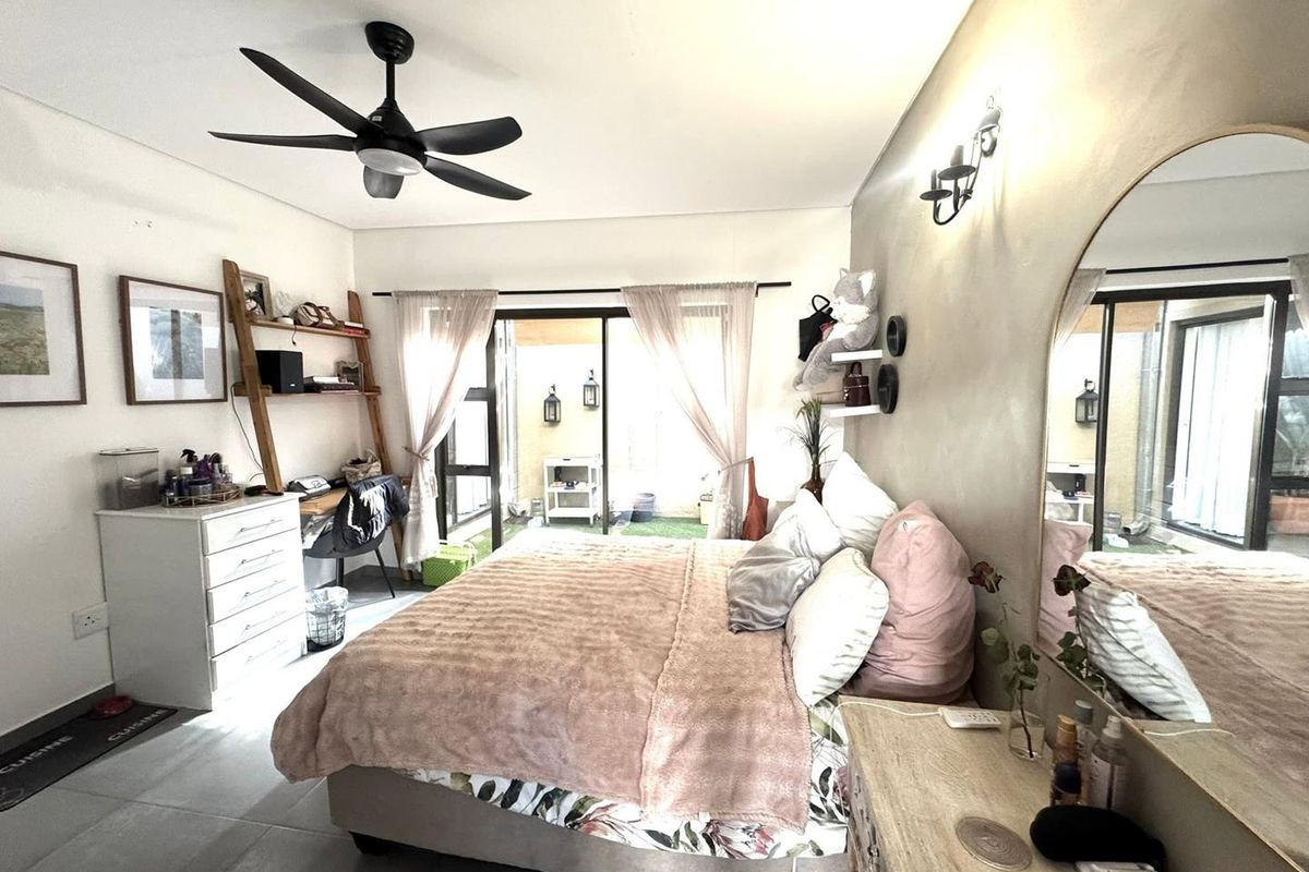 A well-lit bedroom featuring tiled flooring, a modern ceiling fan, and sliding glass doors that provide direct access to an outdoor patio area.
