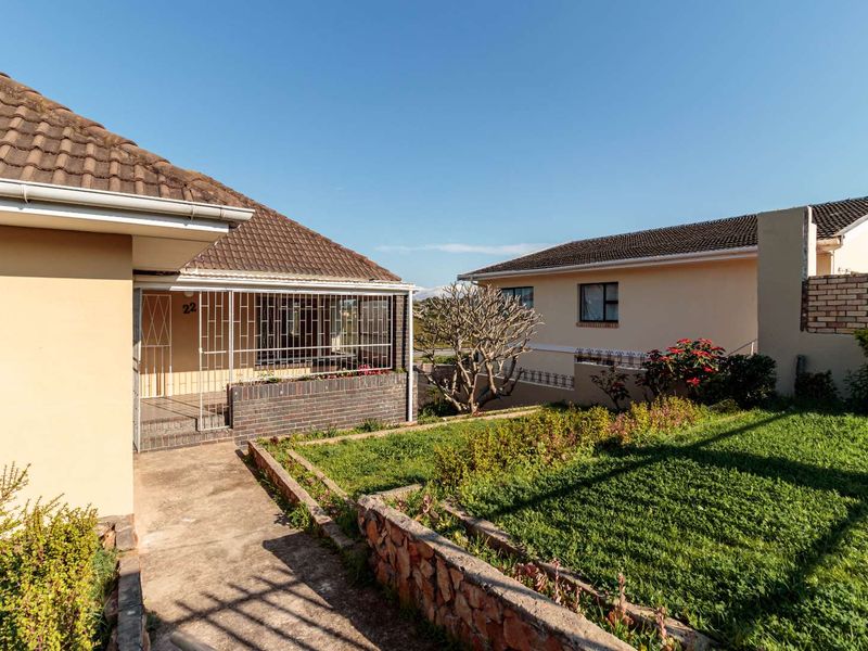Front view of the property featuring a tiled roof, security gate, and a landscaped garden with a concrete walkway.