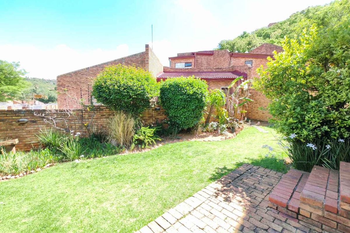 A private rear garden featuring a brick-paved patio, tiered brick steps, and established landscaping against a classic brick townhouse facade.