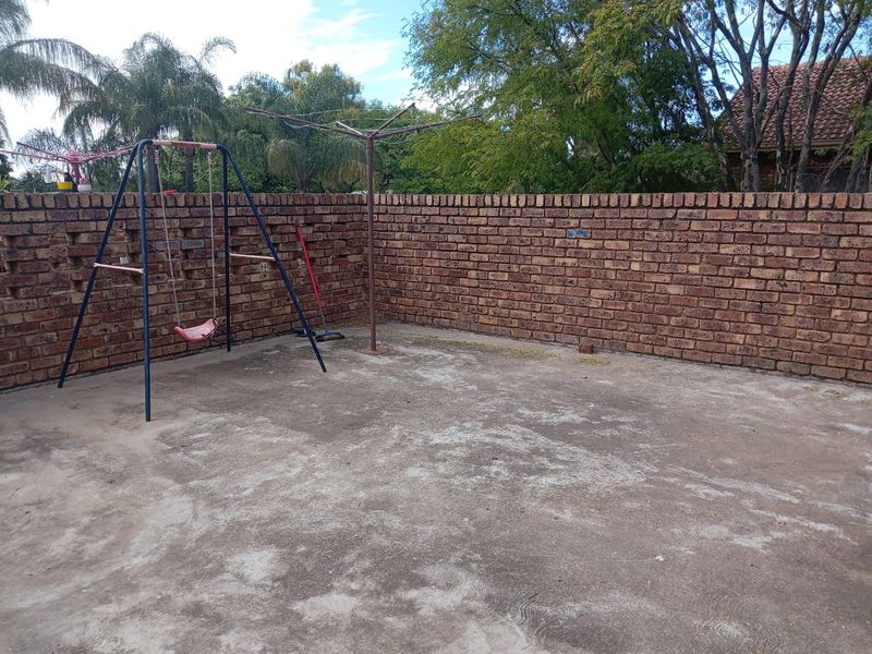 A private outdoor patio area featuring a concrete floor and enclosed by a sturdy brick boundary wall, offering a blank canvas for landscaping.