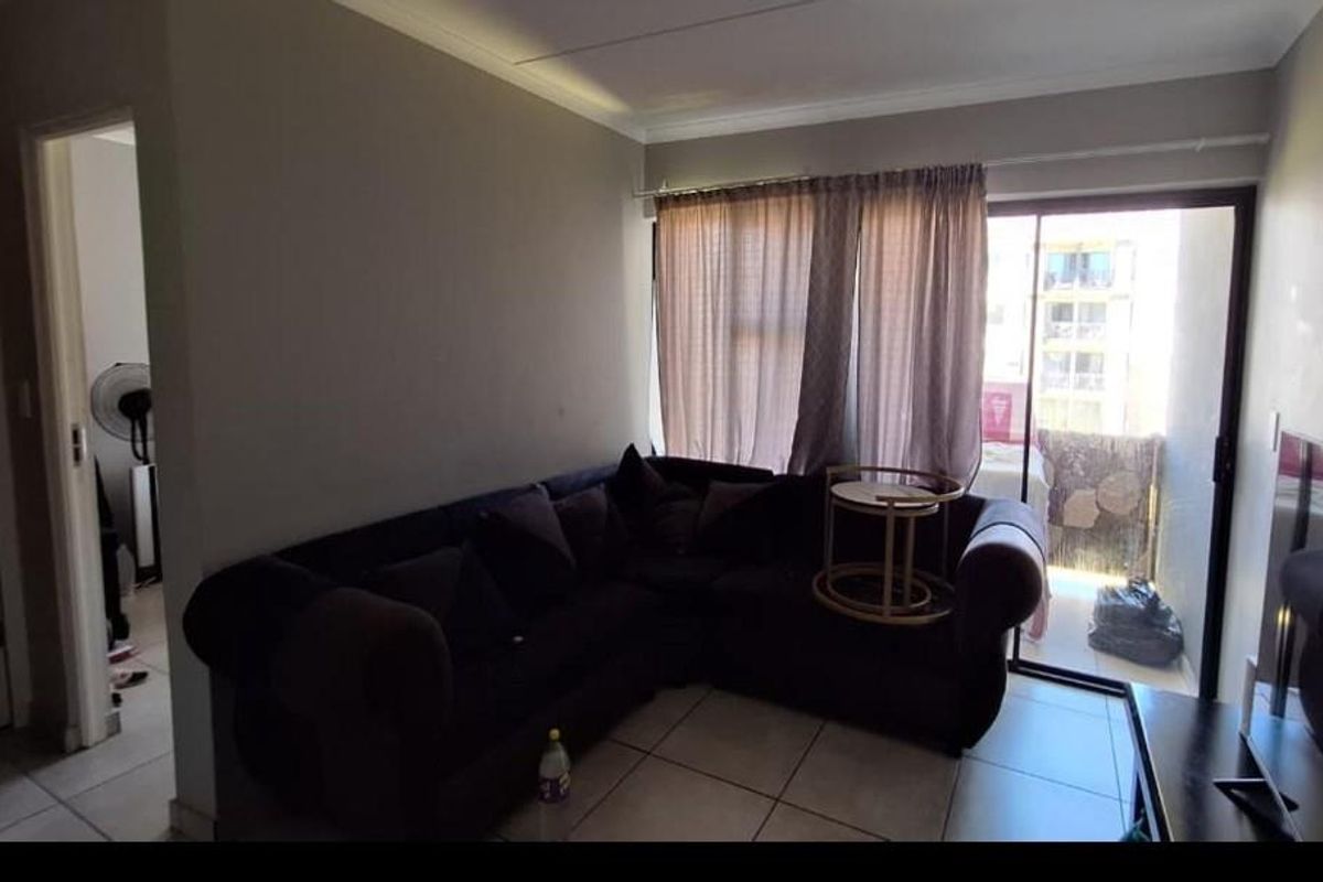 A living room featuring tiled flooring and a sliding glass door that provides access to an outdoor balcony area.