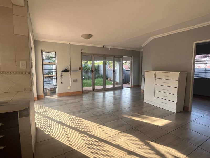 Spacious open-plan living area featuring tiled flooring, neutral walls, and large aluminium sliding doors providing direct access to the rear garden.