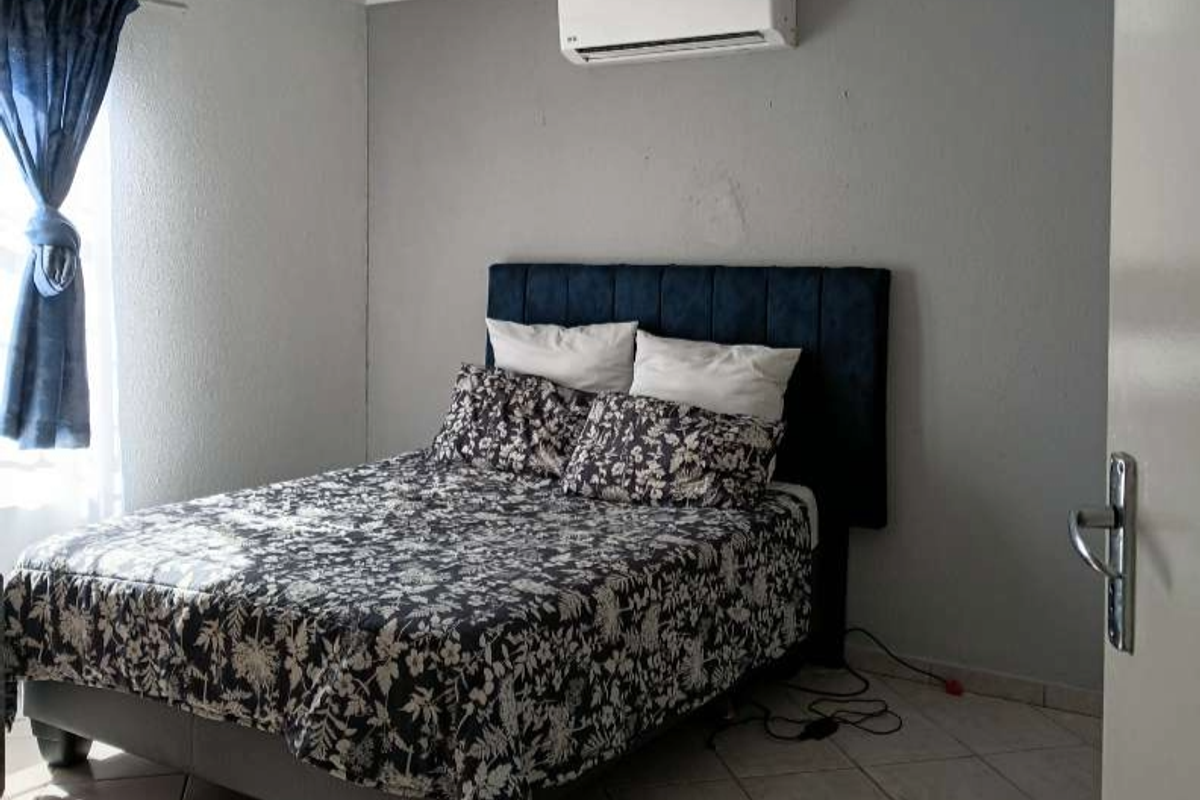 A functional bedroom featuring tiled flooring and a wall-mounted split-system air conditioner.