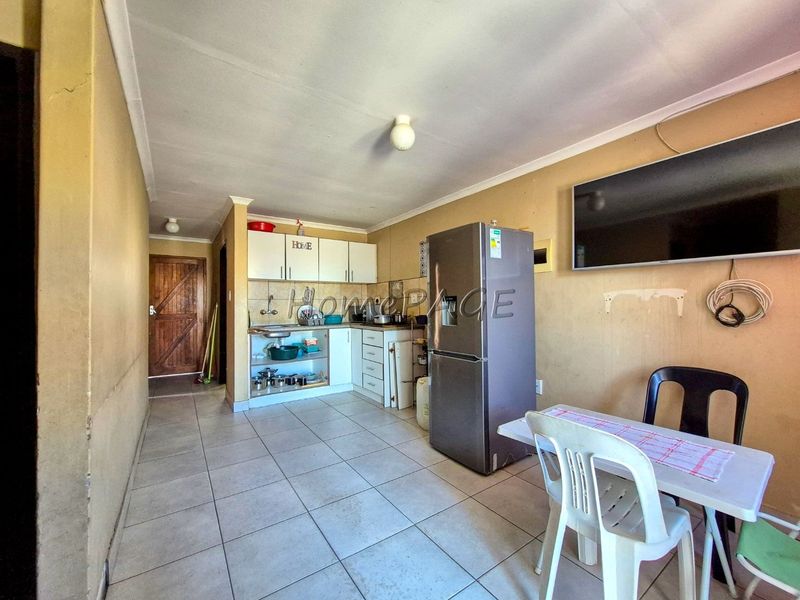 Open-plan kitchen and living area featuring tiled flooring and built-in cabinetry, requiring cosmetic updates to improve the overall condition and aesthetic appeal.
