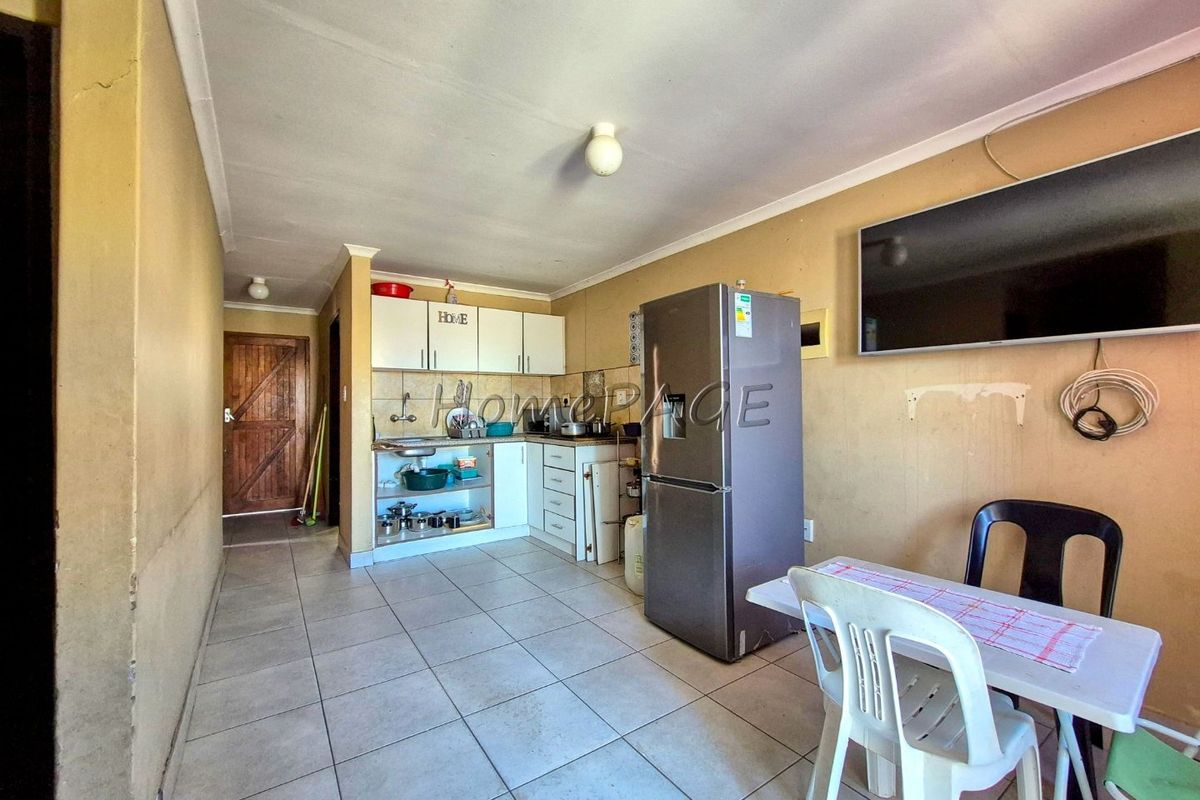 Open-plan kitchen and living area featuring tiled flooring and built-in cabinetry, requiring cosmetic updates to improve the overall condition and aesthetic appeal.