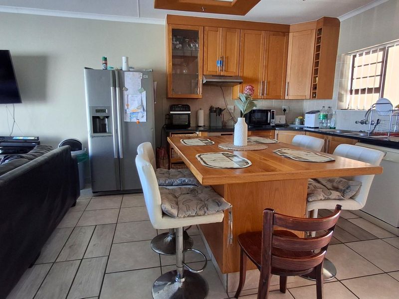Open-plan living and kitchen area featuring wooden cabinetry, a central kitchen island, and tiled flooring throughout.