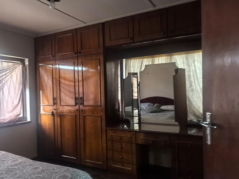 A bedroom featuring extensive built-in wooden cabinetry and a matching integrated vanity unit with a mirror.