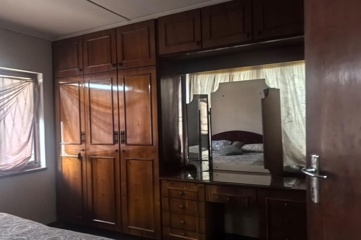 A bedroom featuring extensive built-in wooden cabinetry and a matching integrated vanity unit with a mirror.