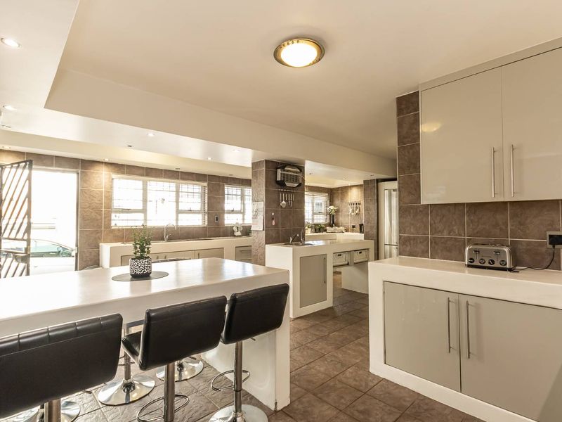 Spacious kitchen featuring modern cabinetry, stone countertops, a breakfast bar, and tiled finishes throughout, offering a functional and well-lit culinary space.