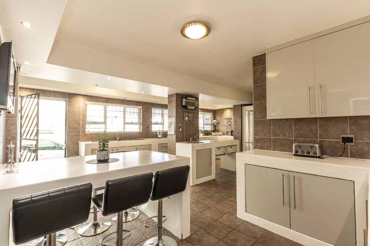 Spacious kitchen featuring modern cabinetry, stone countertops, a breakfast bar, and tiled finishes throughout, offering a functional and well-lit culinary space.