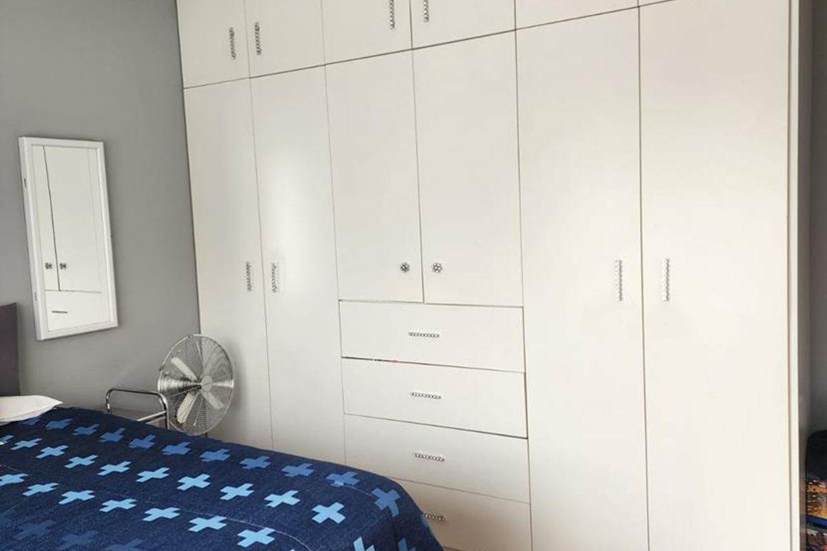 A bedroom featuring extensive floor-to-ceiling built-in white cabinetry with integrated drawers and modern hardware, providing ample storage space.