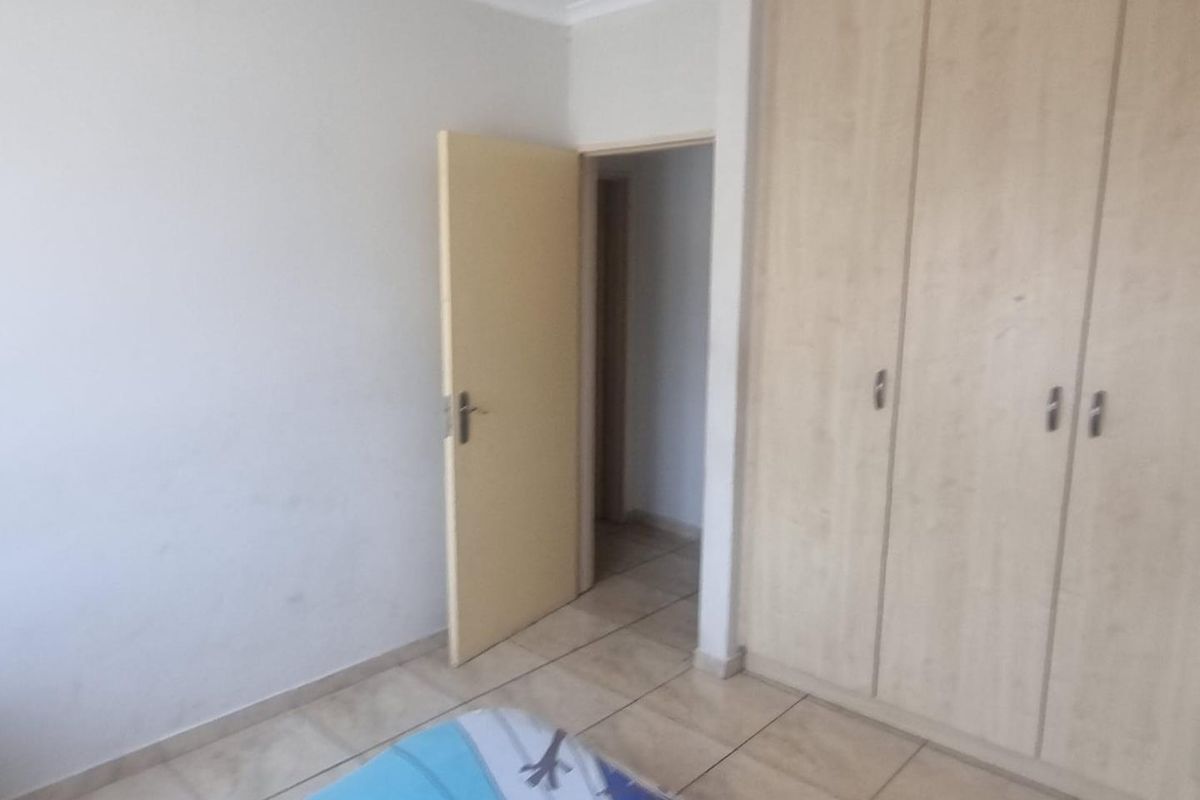 A bedroom featuring built-in cupboards and tiled flooring, providing a functional space with neutral finishes.