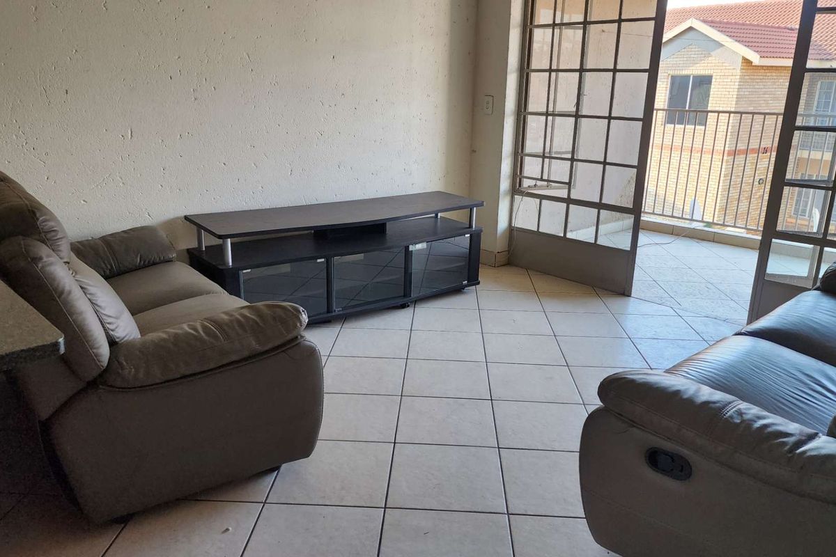 Living room area featuring tiled flooring and direct access to a balcony through a metal-framed glass door.
