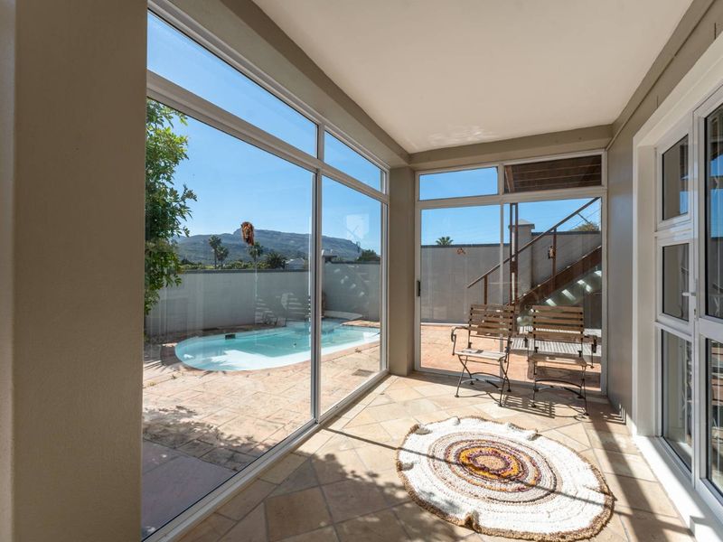 A bright, enclosed patio area featuring tiled flooring and large sliding glass doors that provide direct access and views to the outdoor pool area.