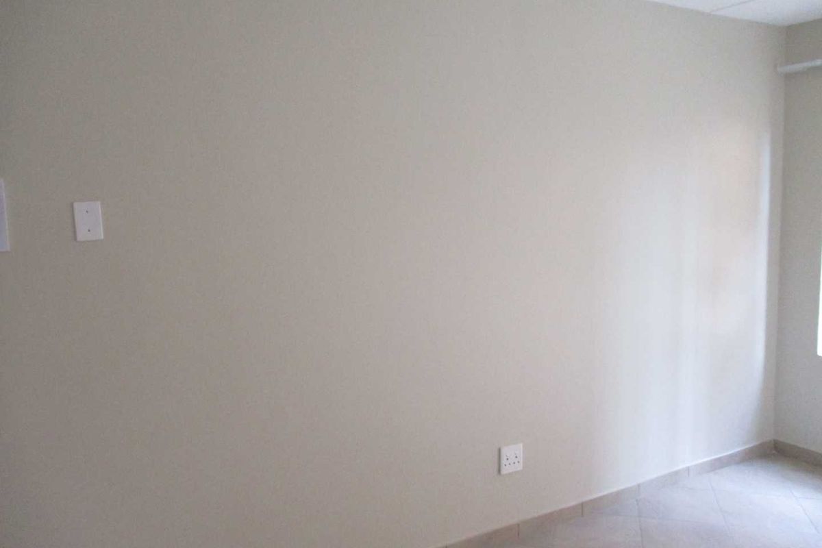 An empty bedroom featuring neutral wall paint, tiled flooring, and standard electrical fixtures.