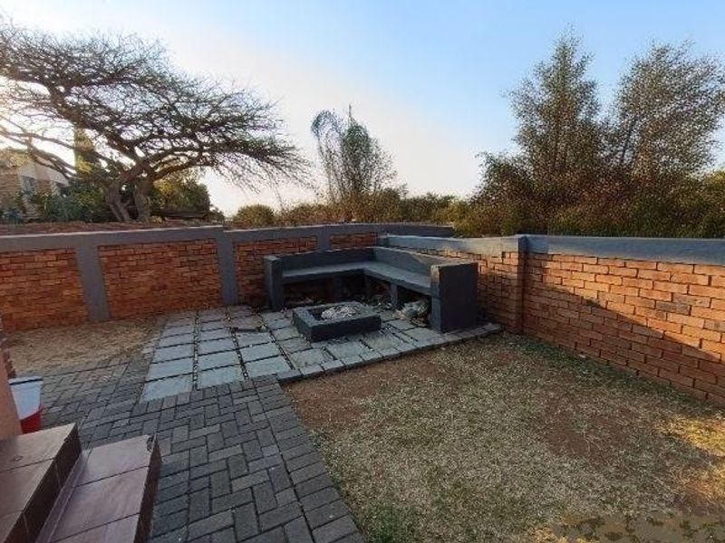 Outdoor patio area featuring a built-in concrete bench, fire pit, and brick boundary walls, providing a functional space for outdoor entertainment.