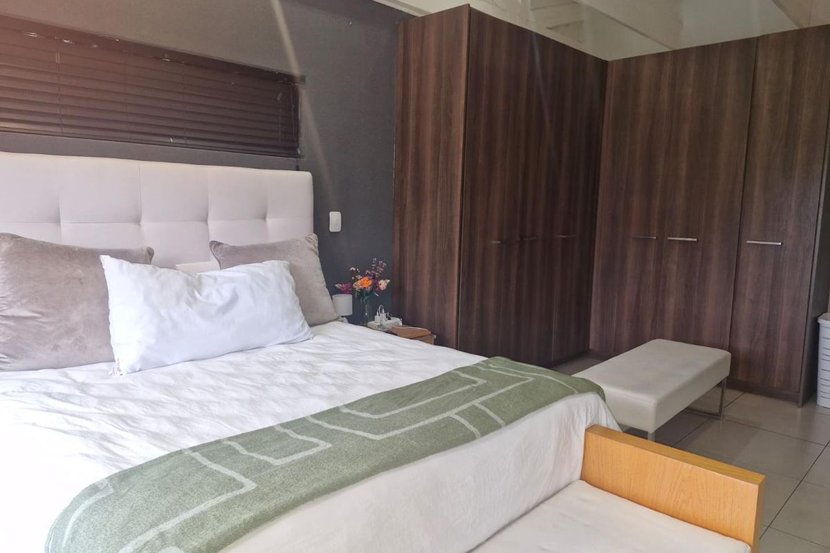 A well-maintained bedroom featuring built-in dark wood cabinetry, tiled flooring, and a neutral color palette.