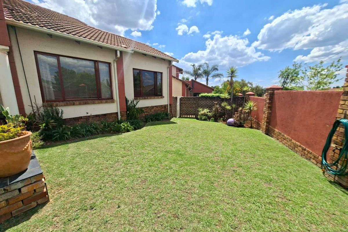 A well-maintained rear garden featuring a manicured lawn, established garden beds, and secure brick boundary walls, providing a private outdoor space.