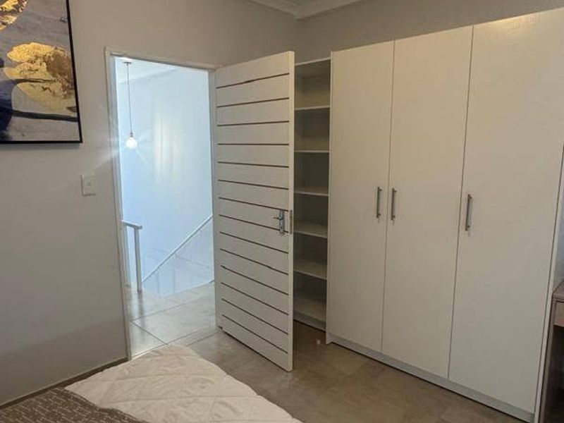 A well-maintained bedroom featuring built-in wardrobes with shelving and tiled flooring, providing ample storage and a clean, functional living space.