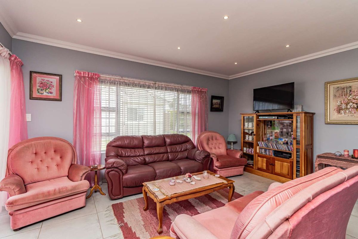 A comfortable living room featuring tiled flooring, recessed downlighting, and large windows with fitted blinds, providing a bright and functional space.