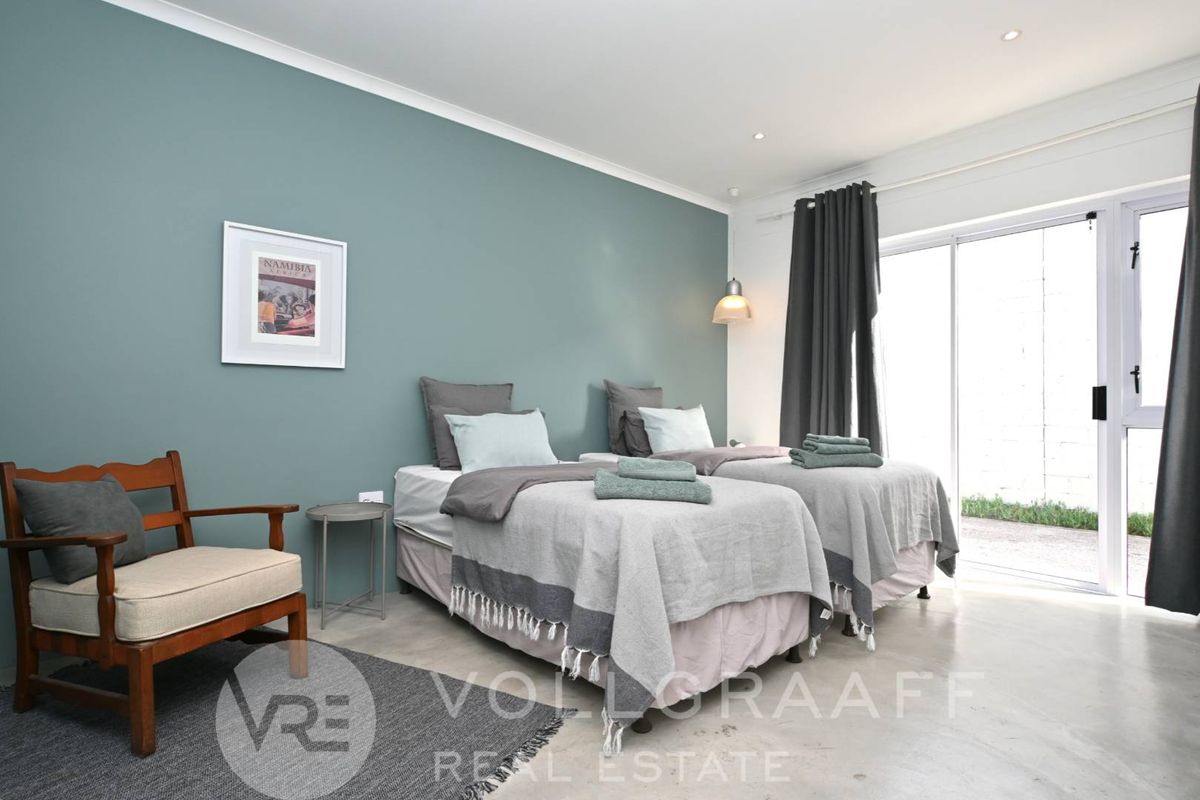 A well-maintained bedroom featuring polished concrete flooring, a feature wall, and sliding glass doors providing direct access to the exterior.