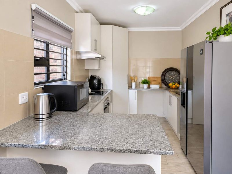 A functional kitchen featuring granite countertops, ample built-in cabinetry, a tiled backsplash, and a breakfast bar area with a window.