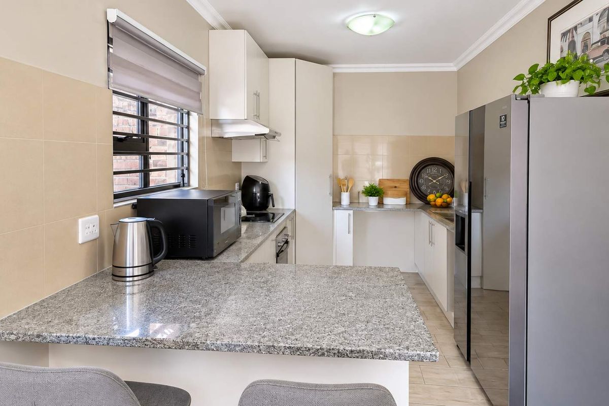 A functional kitchen featuring granite countertops, ample built-in cabinetry, a tiled backsplash, and a breakfast bar area with a window.