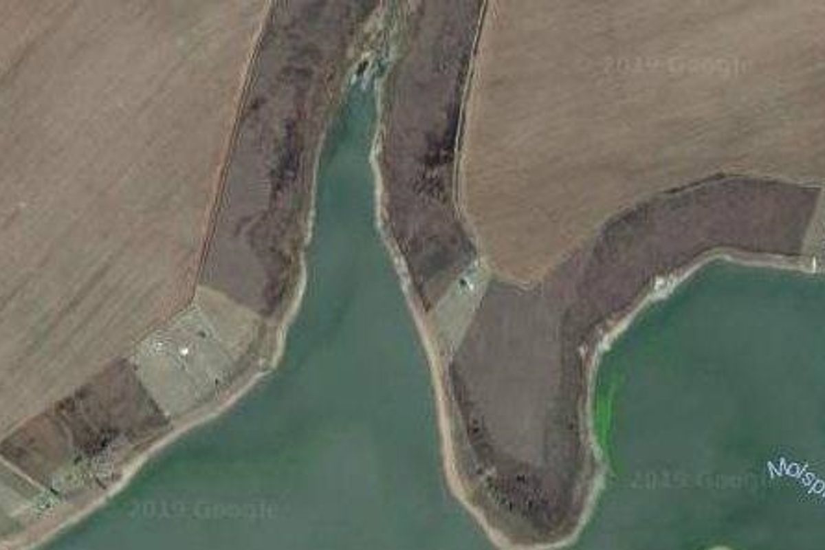 Aerial view of vacant residential land situated along the waterfront, showcasing the natural landscape and surrounding terrain.