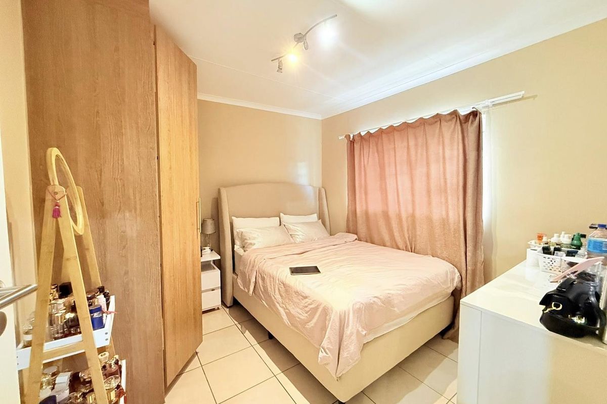 A functional bedroom featuring tiled flooring, built-in wooden cabinetry, and a window with curtain tracks.