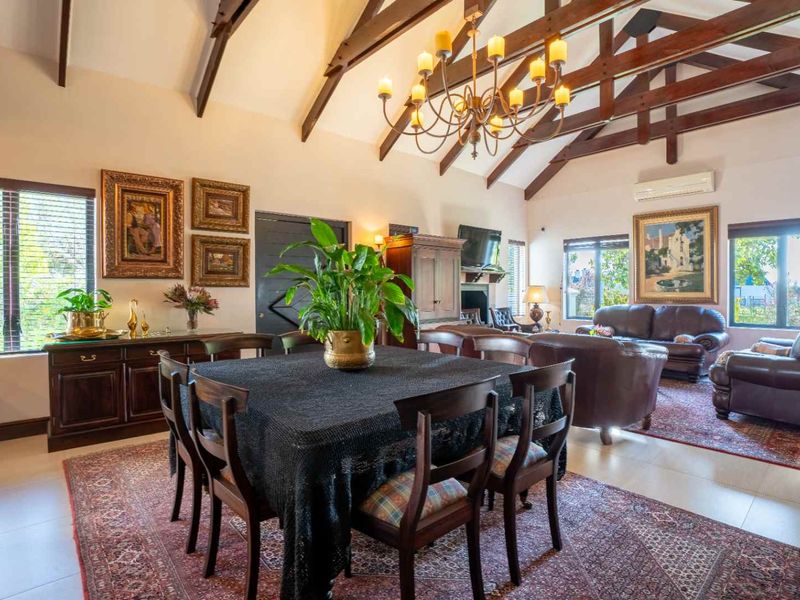 Spacious open-plan living and dining area featuring high vaulted ceilings with exposed timber beams and tiled flooring.