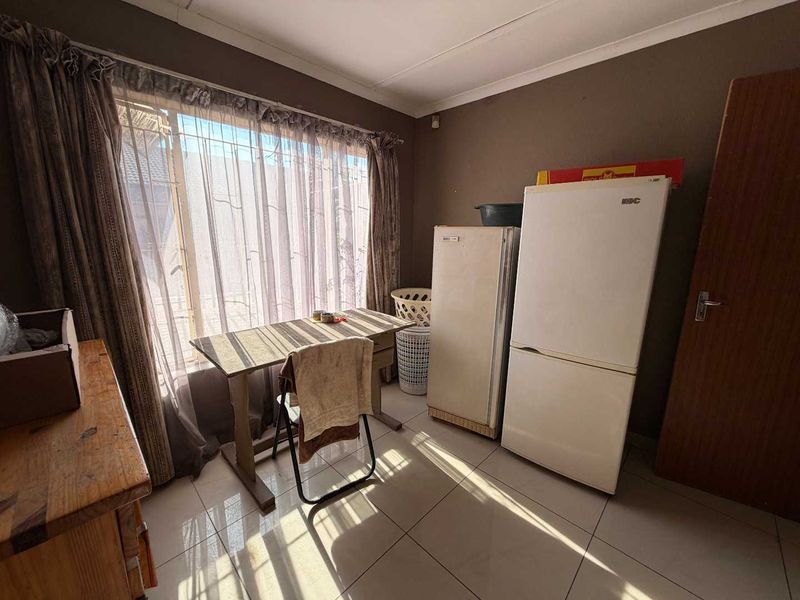 A functional kitchen area featuring tiled flooring and large windows, providing a practical space for food preparation and storage.