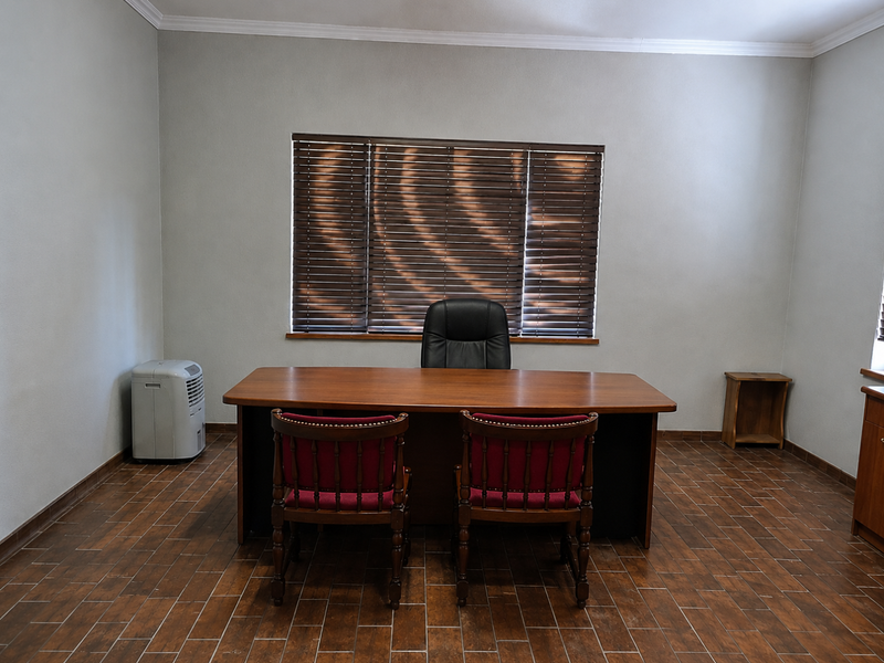 A professional office space featuring tiled flooring, crown molding, and venetian blinds, providing a clean and functional work environment.