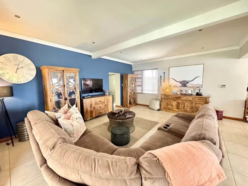 Spacious living room featuring tiled flooring, recessed downlighting, and a bold blue accent wall, creating a comfortable and inviting atmosphere.