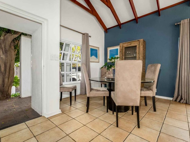 Dining area featuring a vaulted ceiling with exposed timber beams, tiled flooring, and direct access to an outdoor patio space.
