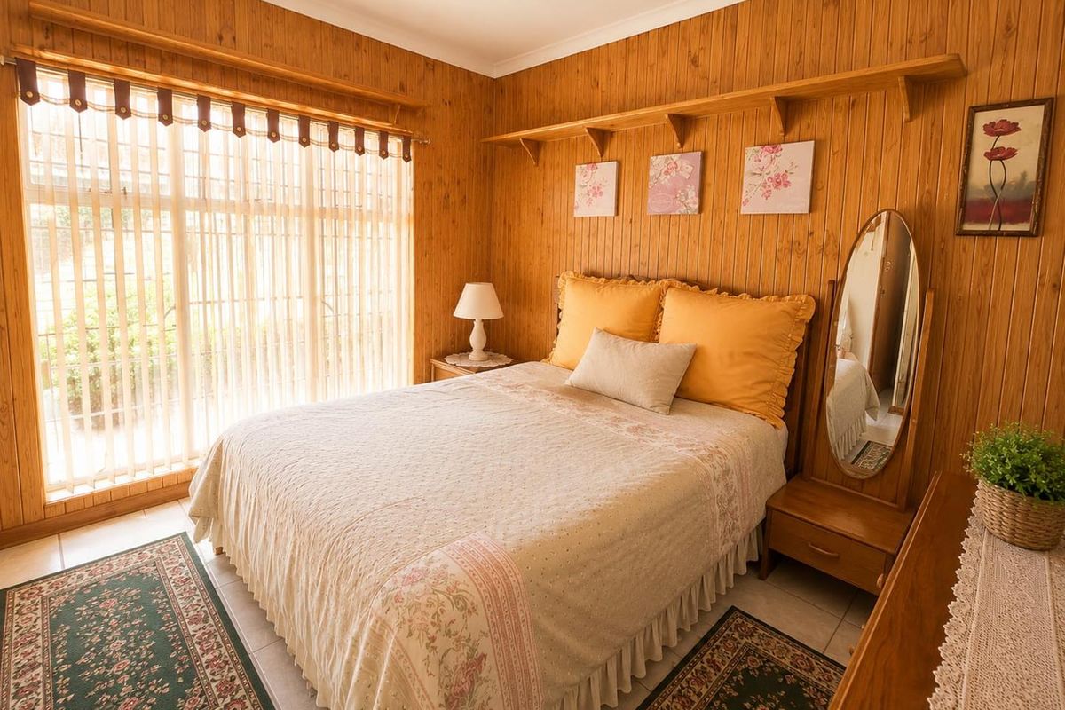 A cozy bedroom featuring warm timber wall paneling, tiled flooring, and large windows with vertical blinds, offering a classic and comfortable living space.