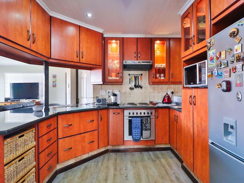 A functional kitchen featuring warm-toned wooden cabinetry, granite countertops, a tiled backsplash, and integrated appliances, offering a practical layout for daily cooking.