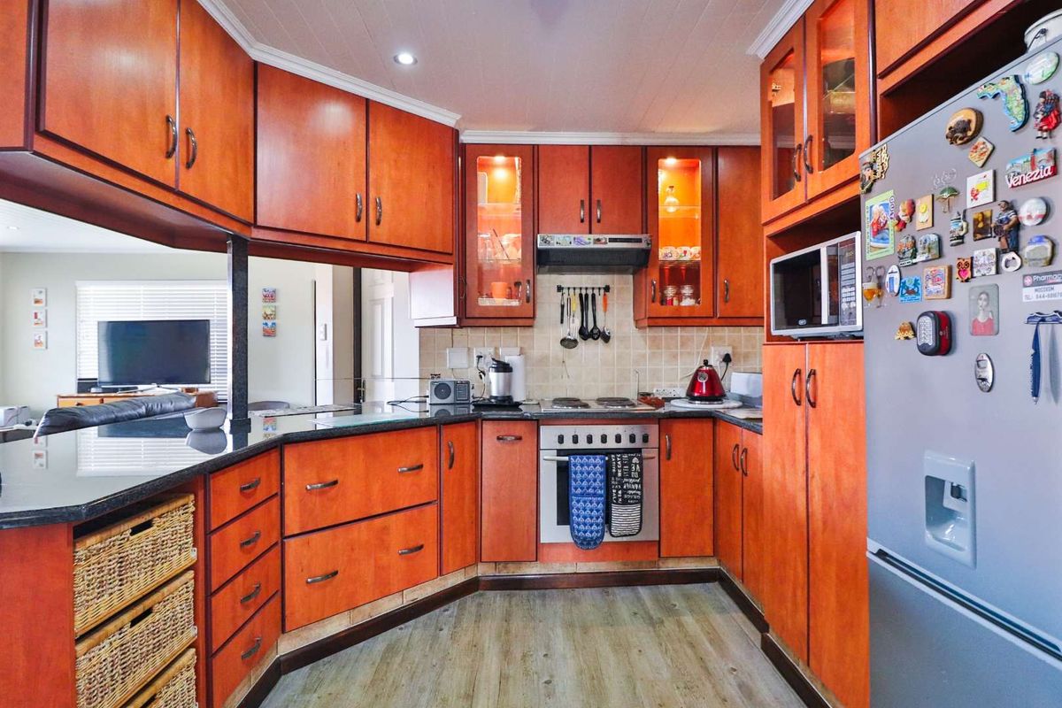 A functional kitchen featuring warm-toned wooden cabinetry, granite countertops, a tiled backsplash, and integrated appliances, offering a practical layout for daily cooking.
