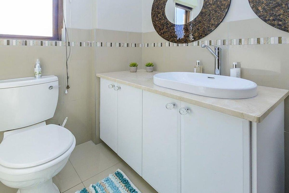 A clean bathroom featuring a modern vessel sink vanity, tiled walls with decorative accents, and a standard toilet.