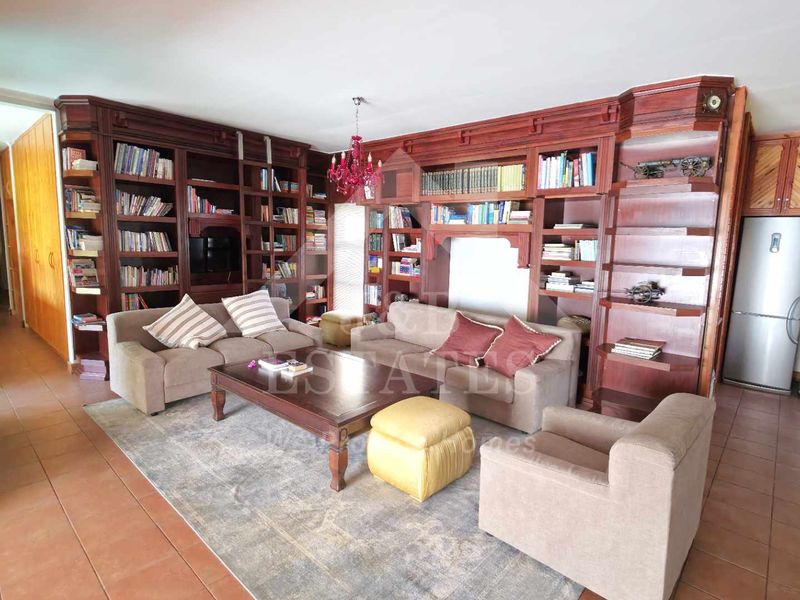 Open plan living area featuring extensive built-in wooden shelving and cabinetry, tiled flooring, and recessed lighting.