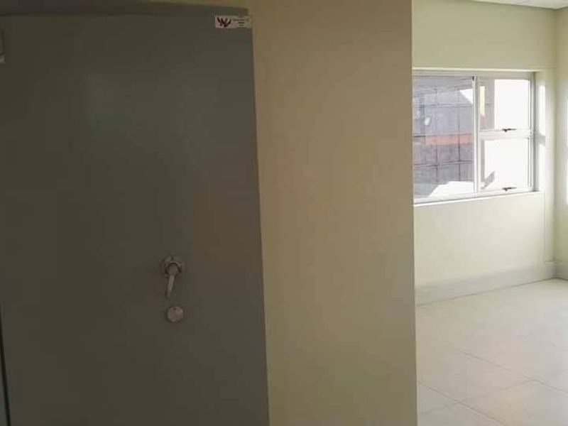 An empty office space featuring tiled flooring, aluminium windows, and a secure heavy-duty steel vault door.