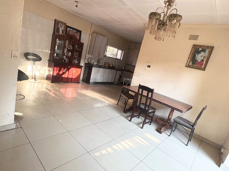 Open-plan living and kitchen area featuring tiled flooring and built-in cabinetry, offering a functional space for dining and food preparation.