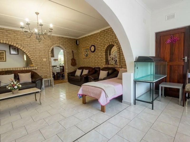 Spacious living area featuring exposed brick walls, arched architectural details, and neutral ceramic floor tiles, offering a classic and character-filled interior space.