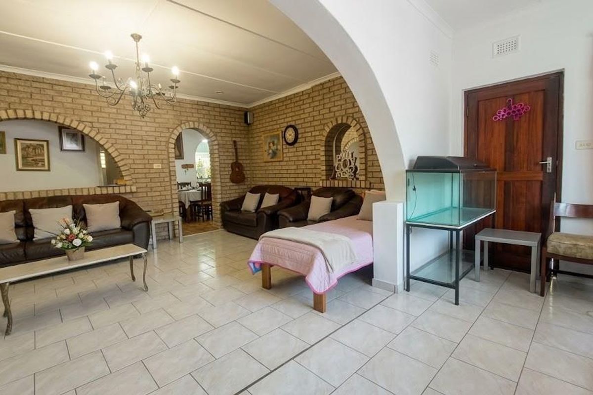 Spacious living area featuring exposed brick walls, arched architectural details, and neutral ceramic floor tiles, offering a classic and character-filled interior space.